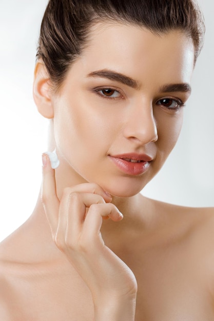 Facial Care Female Applying Cream and Smiling Portrait Of Young Woman With Cosmetic Cream