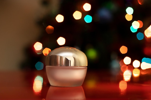 Facial cosmetics moisturizer A jar of lotion against the background of a garland