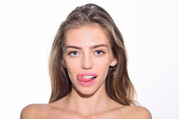 Facial expression, emotion, beauty and people concept - happy woman, sexy girl showing tongue. Emotional girl licking lips. Seductive girl with funny face, long hair, bare shoulders shows tongue.