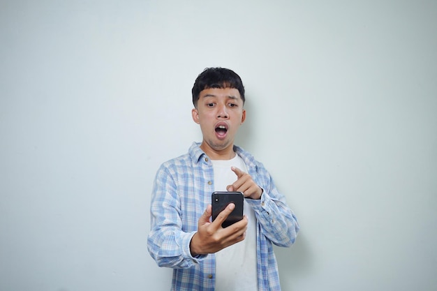 Facial expression of very shocked asian man using mobile phone isolated on white background