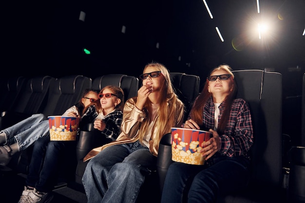 Foto espressioni facciali gruppo di ragazzi seduti al cinema e guardando film insieme