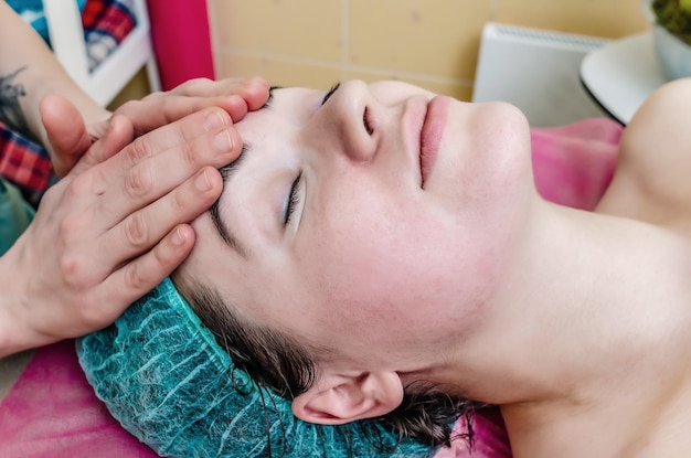 Facial massage Facial skin care Profile of a woman with the hands of a masseuse