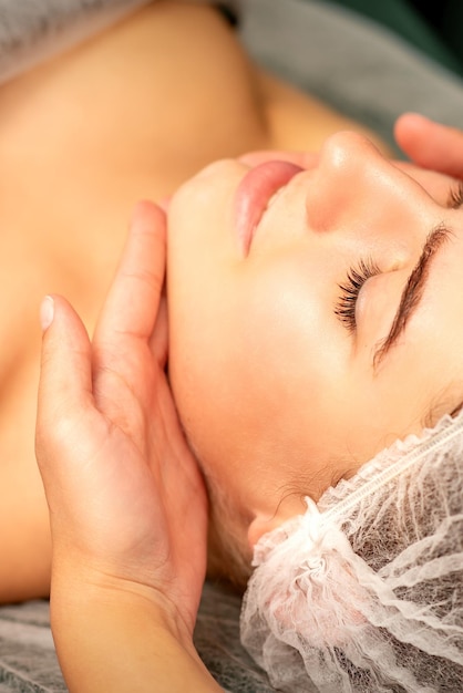 Facial massage Hands of a masseur massaging neck of a young caucasian woman in a spa salon the concept of health massage