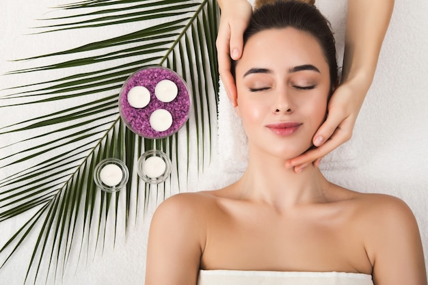 Facial massage. Spa, resort, beauty and health concept. Beautiful woman getting professional face treatment, top view, copy space