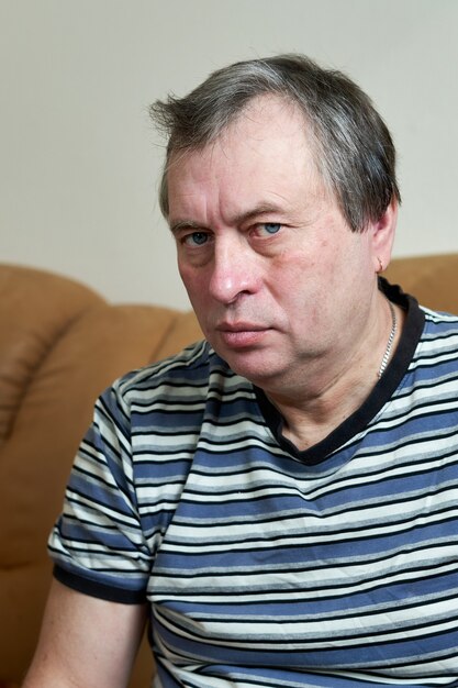 Facial portrait of an elderly man of retirement age. Vertical shot, looking at the camera