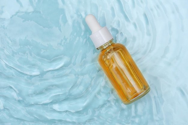 Facial serum on blue water background copy space