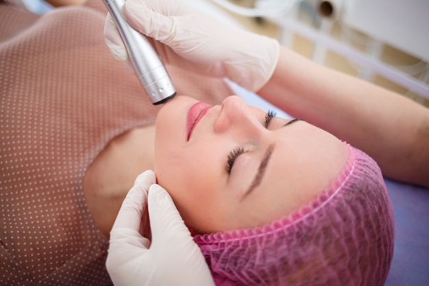 Facial skin care. Young beautiful woman with gets procedure in a beauty salon. Ultrasonic anti-aging cavitation, rejuvenation, lifting procedure. Beauty concept