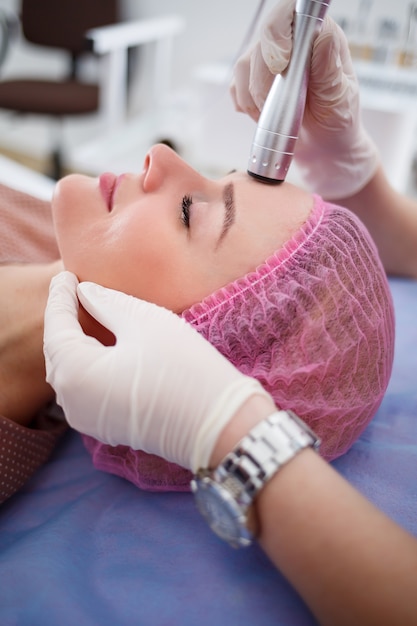 Facial skin care. Young beautiful woman with gets procedure in a beauty salon. Ultrasonic anti-aging cavitation, rejuvenation, lifting procedure. Beauty concept