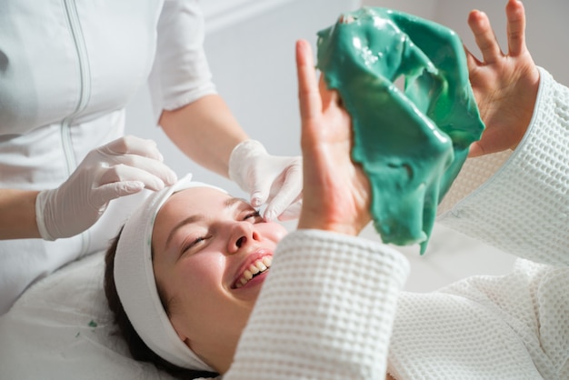 Cura della pelle del viso una maschera viene applicata al viso di una donna in una clinica di cosmetologia da vicino