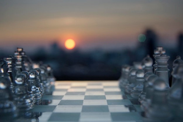 Facing between dark and white side chess with blue sun and city in background at beautiful sunset