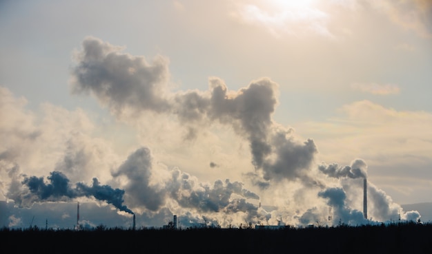 Factory chimneys pollute the atmosphere with dense smoke.