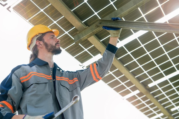 工場エンジニアの男性が太陽電池パネルの建設をチェックして修理する 労働者は再生可能エネルギーの太陽光発電所で働く 持続可能性のための太陽電池産業