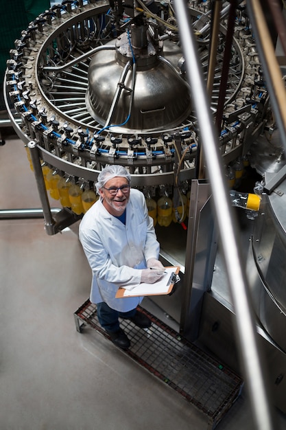 Factory engineer monitoring filled juice bottle on production line