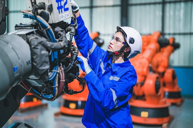 Factory engineer woman inspecting on machine with smart tablet Worker works at machine robot arm