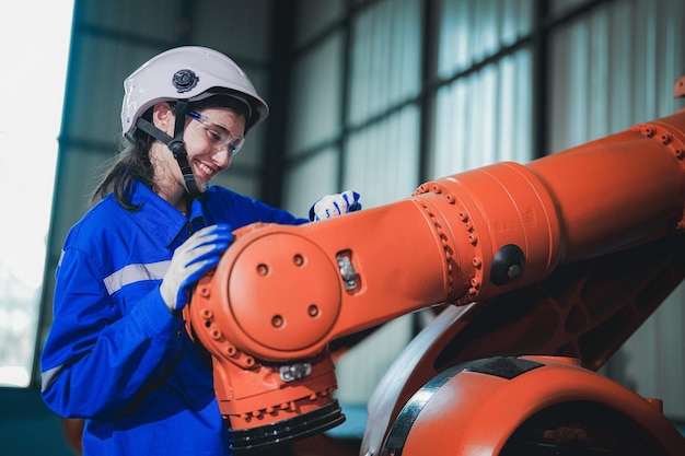 Photo factory engineer woman inspecting on machine with smart tablet worker works at machine robot arm