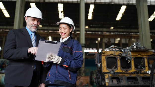 Factory manager and female engineer in factory and inspecting\
factory in industry plant background