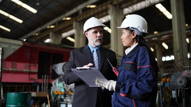 Factory manager and female engineer in factory and inspecting\
factory in industry plant background