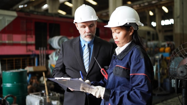 Factory manager and female engineer in factory and inspecting\
factory in industry plant background