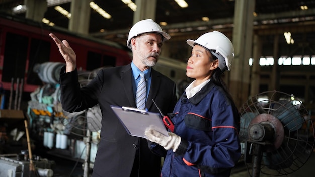 Factory manager and female engineer in factory and inspecting factory in industry plant background
