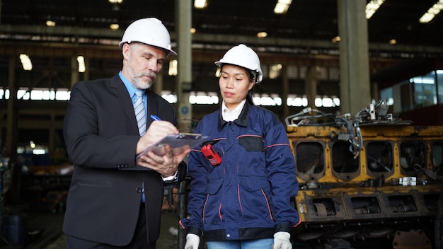 Factory manager and female engineer in factory and inspecting\
factory in industry plant background