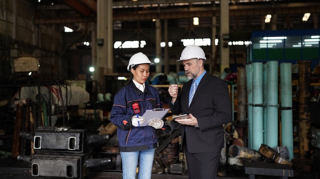 Factory manager and female engineer in factory and inspecting\
factory in industry plant background