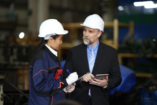 Factory manager and female engineer in factory and inspecting\
factory in industry plant background