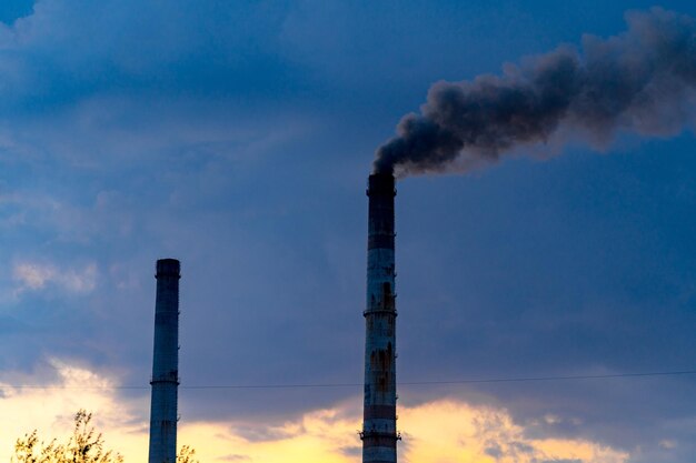 Factory pipes and white smoke floating in the air industrial\
tube and smoke from chimney with cloudy cold day on the\
background