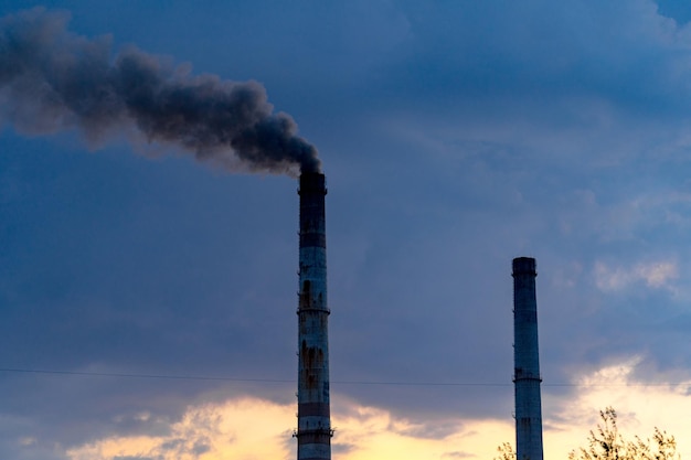 Tubi di fabbrica e fumo bianco che fluttuano nell'aria. tubo industriale e fumo dal camino con una giornata fredda e nuvolosa sullo sfondo.