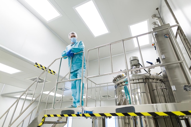 Factory worker in blue suit standing on ladder