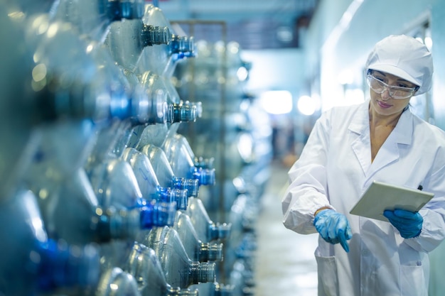 Photo factory worker checking water bottles in the warehouse at the industrial factory