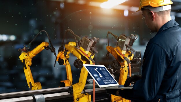 Factory worker control robotic arm in factory