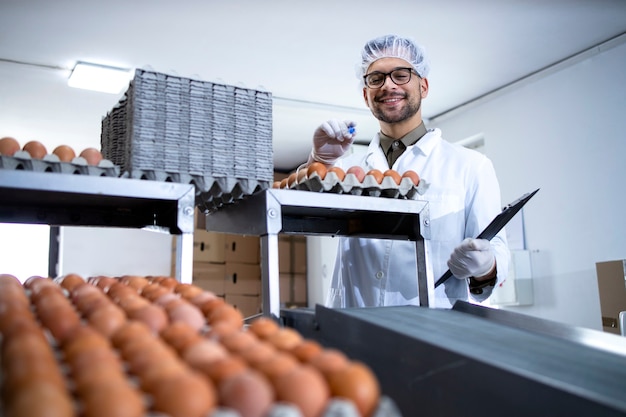 식품 가공 공장에서 계란의 품질을 검사하고 확인하는 체크리스트를 들고 공장 노동자.