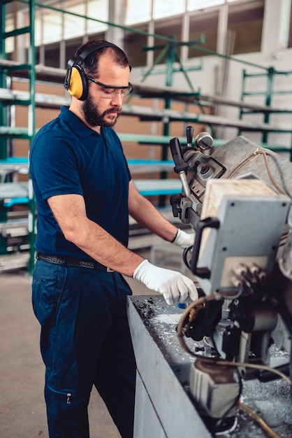 Factory worker operating band saw cutting machine