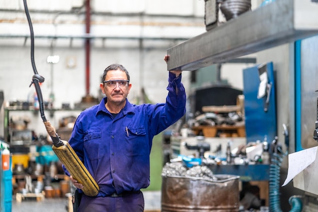 Factory worker operator in the numerical control sector delivering a raised metal part on a machine to a client industrial factory