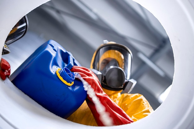 factory worker in protection hazmat suit and gas mask pouring chemicals into barrel in factory