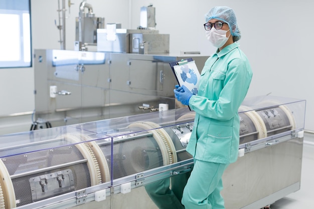 Factory worker standing near machine with tablet