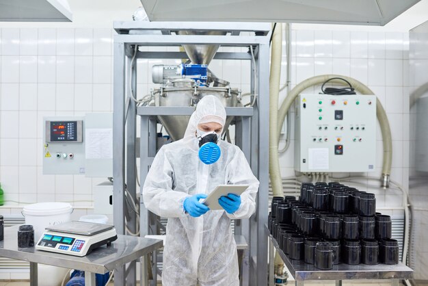 Factory worker standing and using tablet