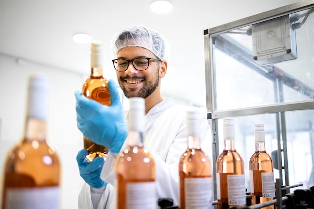 Factory worker or technologist checking quality of bottled wine in alcohol beverage bottling factory
