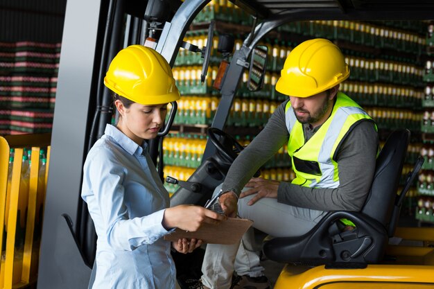 Factory workers checking record on clipboard in factory