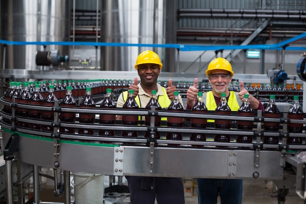 Factory workers showing their thumbs up at drinks production line