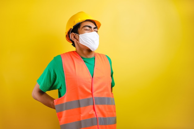 Gli operai sono stanchi e infiammano i muscoli della schiena per il duro lavoro. manodopera in fabbrica con sintomi di dolore lombare su sfondo giallo yellow