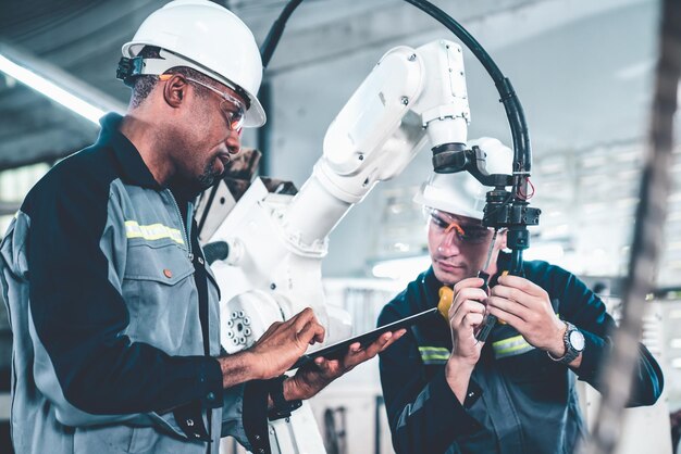 Заводские рабочие, работающие с искусной роботизированной рукой в мастерской