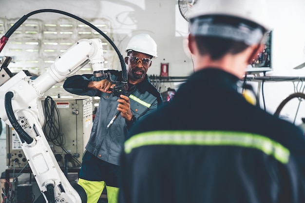 Factory workers working with adept robotic arm in a workshop