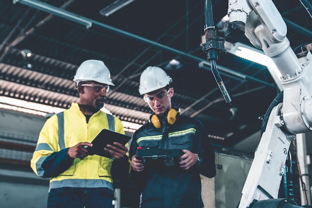 Factory workers working with adept robotic arm in a workshop