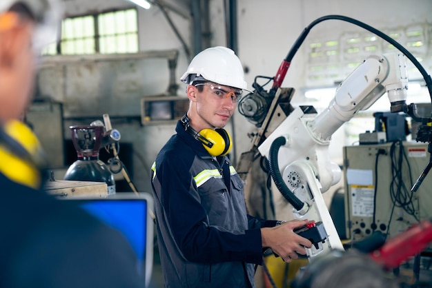 Factory workers working with adept robotic arm in a workshop