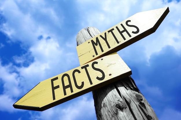 Photo facts myths wooden signpost with two arrows and sky in background