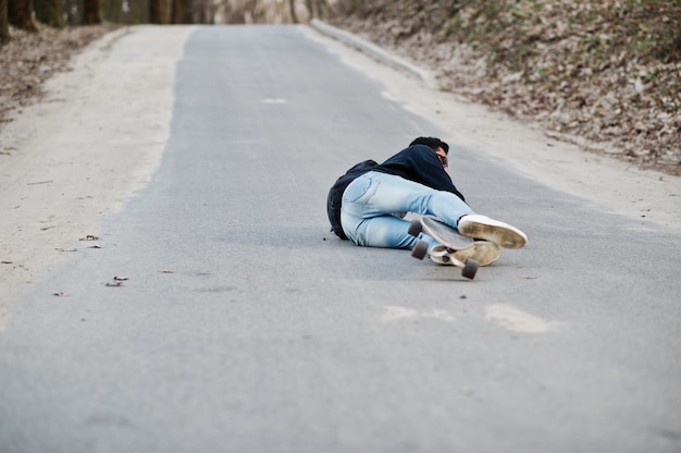 Fail падает со скейтборда. Уличный стиль арабского человека в очках с longboard longboarding вниз по дороге.