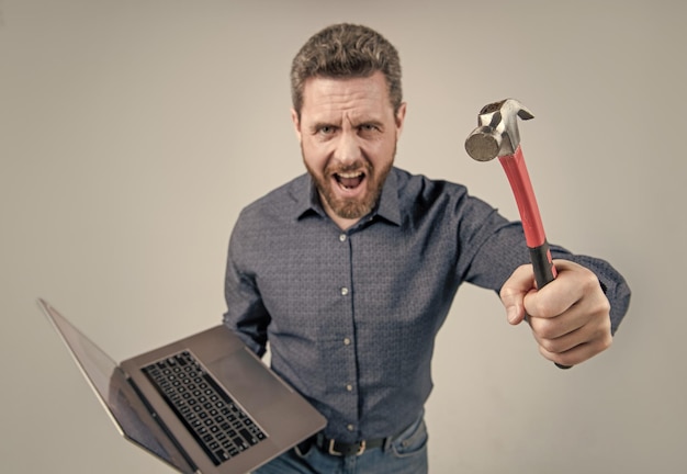 Failed to complete a task angry man shout holding hammer and
laptop computer rage feeling angry