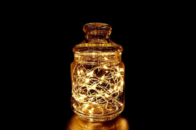 Fairy light string in glass jar on black background