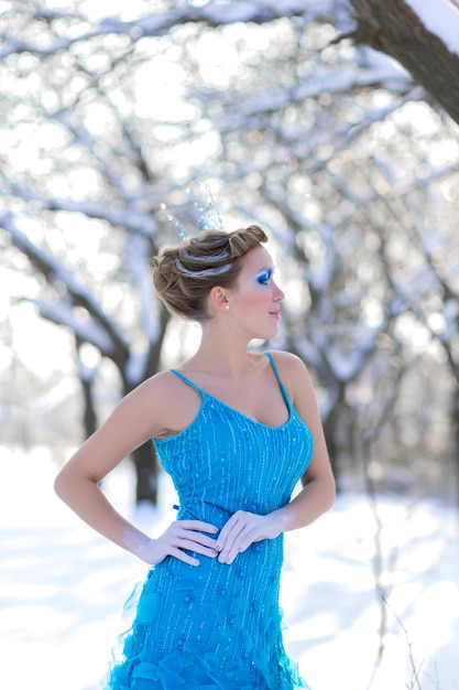 Cosplay da favola della regina del ghiaccio donna con l'abito in posa nella foresta innevata